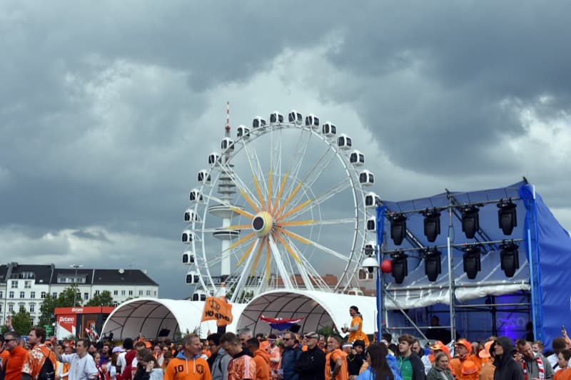 Riesenrad und Fanmenge in oranger Niederlande-Kleidung beim Fan Fest auf dem Hamburger Heiligengeistfeld.