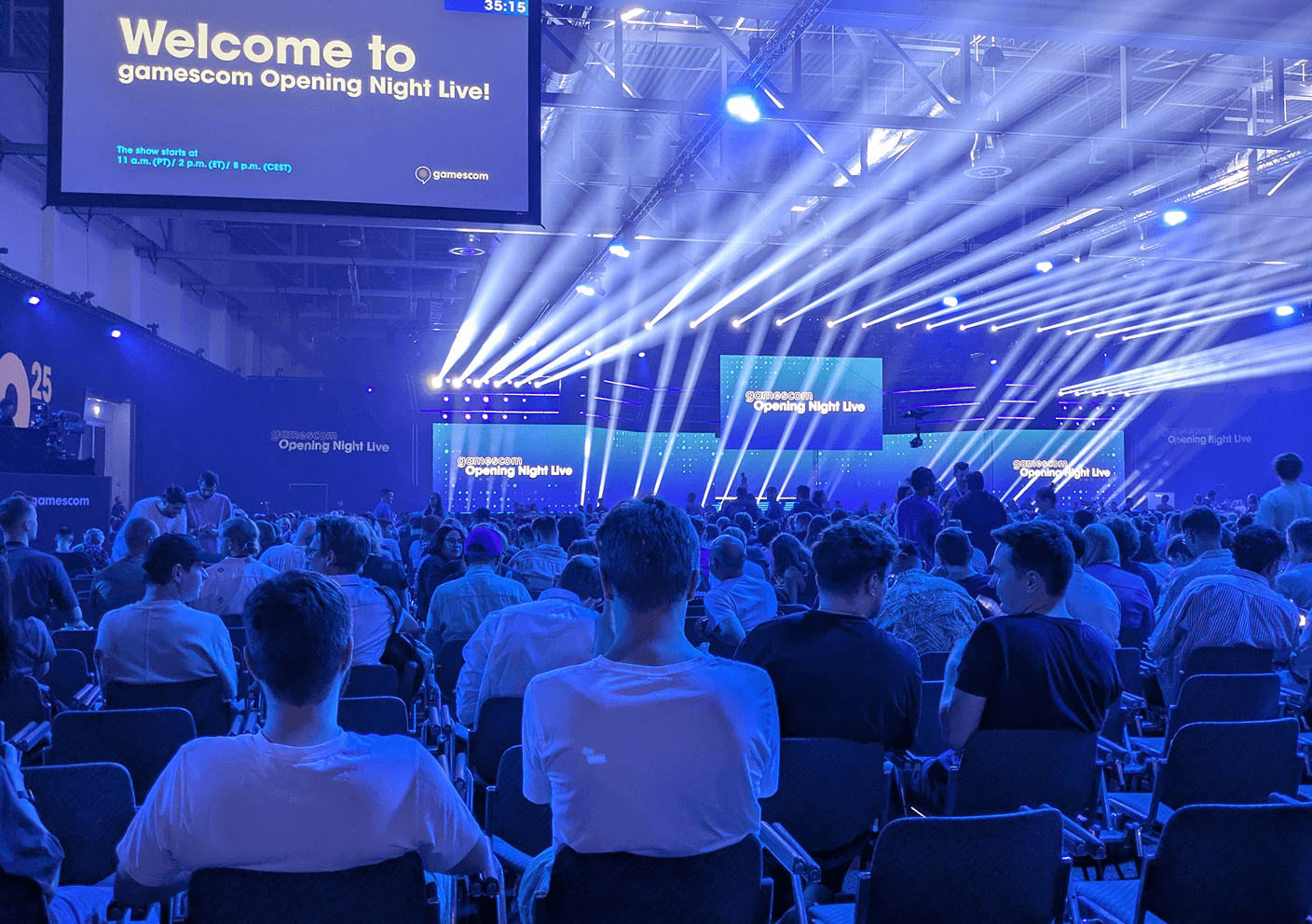 Publikum sitzt vor einer Bühne mit Lichtern, große Leinwand zeigt „Welcome to gamescom Opening Night Live!“.