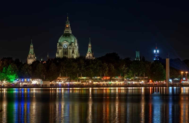 Hannoveraner Neues Rathaus bei Nacht mit beleuchtetem Maschseefest und Spiegelung im Wasser.