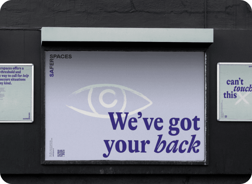 Werbeposter an einer Außenwand mit dem Slogan 'We've got your back' in großen lila Buchstaben auf einem lavendelfarbenen Hintergrund. Über dem Text ist ein stilisiertes weißes Auge abgebildet. Im oberen linken Bereich des Posters steht das Log von 'saferspaces'.